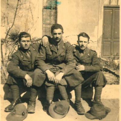 1941 a Fiume tre soldati in divisa seduti davanti ad una casa, tra questi è riconoscibile Umberto Tamburini con appoggiato a terra il cappello degli alpini
