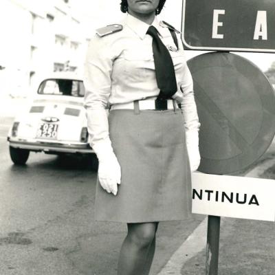 Un immagine del 1973 dell'allora Agente Rita Rotelli in via Circonvallazione Occindetale a lato di un cartello stradale. Sullo sfondo gli edifici di via Circonvallazione Occidentale 