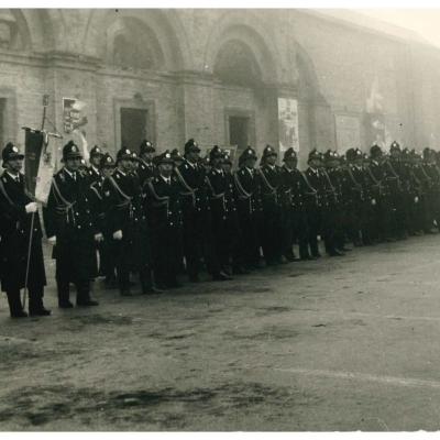 Foto del plotone schierato a lato del teatro Galli in piazza Malatesta in occasione della festa del Corpo per la ricorrenza di san sebastiano nel 1961.  