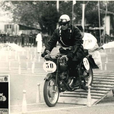 Il Vigile Corbelli in sella ad una moto Guzzi in occasione di una gara di regolarità tenutasi a Bologna nel 1961 in occasione del centenario della Fondazione del Corpo. Sullo sfondo il percorso delineato con i birilli 