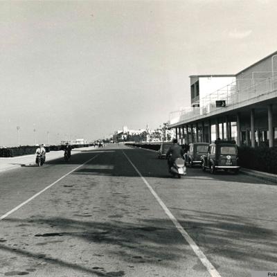 un'immagine del lungomare Tintori mentre transitano alcuni veicoli davanti ai negozi del civico 43, a sinistra la spiaggia. Il tratto di strada attualmente è stato inglobato nel parco del mare     