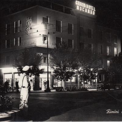 1951. immagine notturna di piazza Tripoli con un Vigile Urbano con lo spallaccio davanti alla coppa rotatoria con le indicazioni stradali che controlla il traffico. Sullo sfondo il Grand Hotel Mocambo