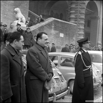 Immagine del Sindaco Walter Ceccaroni con il Comandante Teodoro Nataloni, vestito in alta uniforme, in piazza Cavour davanti al palazzo del Podestà. Sullo sfondo alcuni cittadini che osservano la manifestazione ( 24 gennaio 1960 )