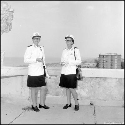 Immagine di due Vigilesse in divisa sulla terrazza del Grand Hotel di Rimini. Il parapetto della terrazza è in cemento, sullo sfondo a sinistra il lungomare e il condominio di viale Vespucci 10 ( luglio 1969 )