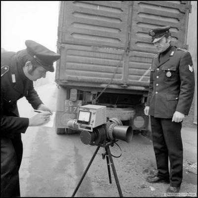 immagine di due Vigili Urbani intenti a rilevare le misure e ad annotarle di gas di scarico di un camion con l'opacimetro ( 1975 ).  