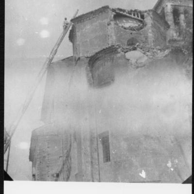 immagine esterna di una Chiesa con danni dovuti al terremoto del 1916 nell'abside e nel tetto. I pompieri, con l'uso si scale, stanno salendo sul tetto  