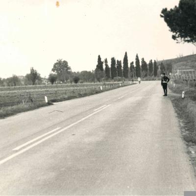 foto panoramica di via Marecchiese in direzione Rimini al Km 83 + 400 ( 1969 ). Si vedono i campi coltivati ai lati della carreggiata. Sul lato destro della strada un Vigile Urbano. Sullo sfondo la collina di Vergiano