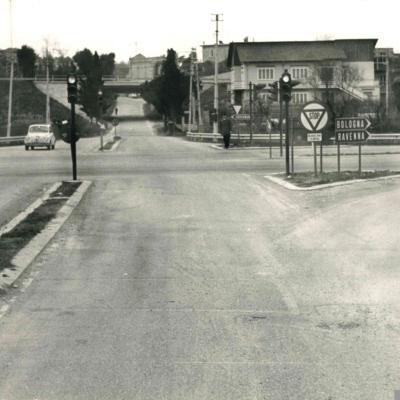 ripresa fotografica della via Covignano intersezione semaforica con la Nuova Circonvallazione ( 1967 ). A lato del semaforo un Vigile Urbano, sullo sfondo il ponte dell'autostrada e l'inizio della salita per andare a Covignano. 