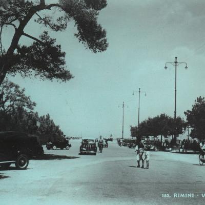 1941. Traffico nel viale a mare ora viale Beccadelli. Un Vigile a lato della carreggiata controlla il traffico veicolare e pedonale. Sullo sfondo la spiaggia