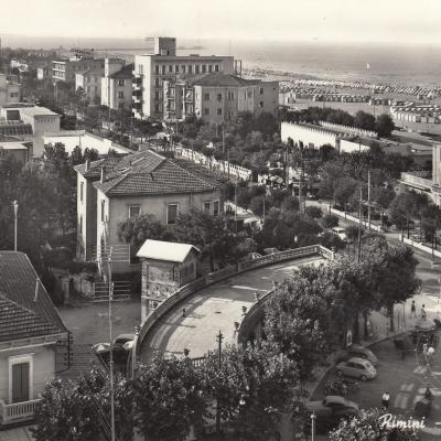 1961. Immagine panoramica di piazza Tripoli con prospettiva su viale Vespucci con le ville. All'incrocio un Vigile controlla il traffico. Sullo sfondo di vede l'oriental park, la spiaggia con le cabine e il mare   