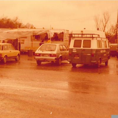 immagine panoramica campo base. In primo piano tra auto tra cui la Zebra 14 dei Vigili Urbani di Rimini ( furgone Fiat 850T ), sullo sfondo la cucina da campo con persone in fila in attesa della distribuzione del cibo. Terremoto in Irpinia nel 1980 
